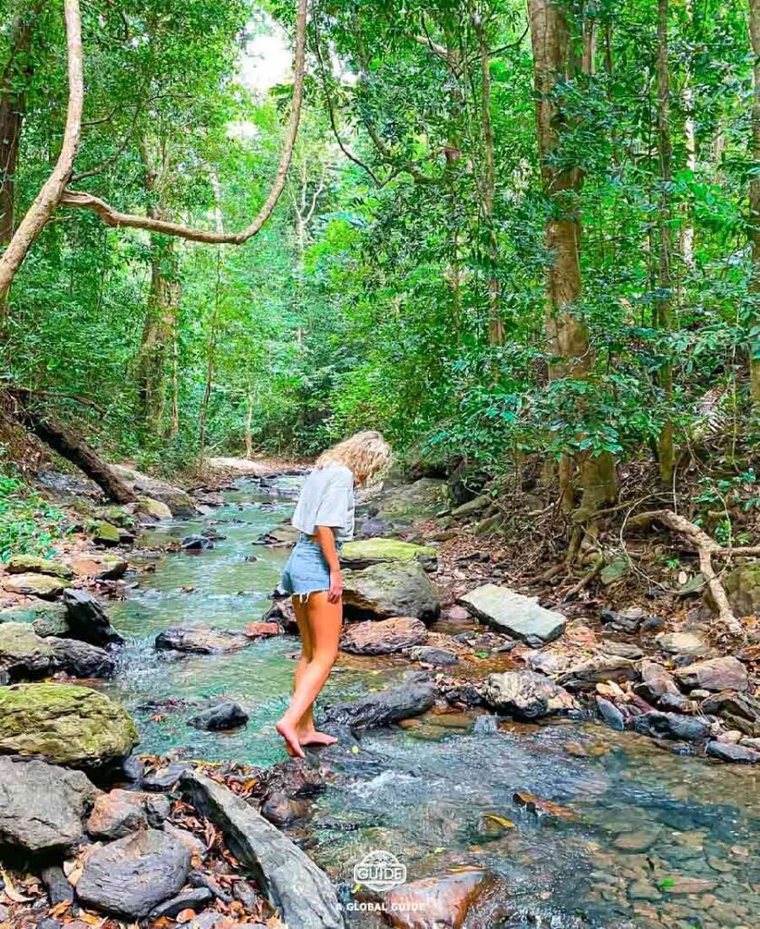 Girl standing in a river in the middle of the jungle.