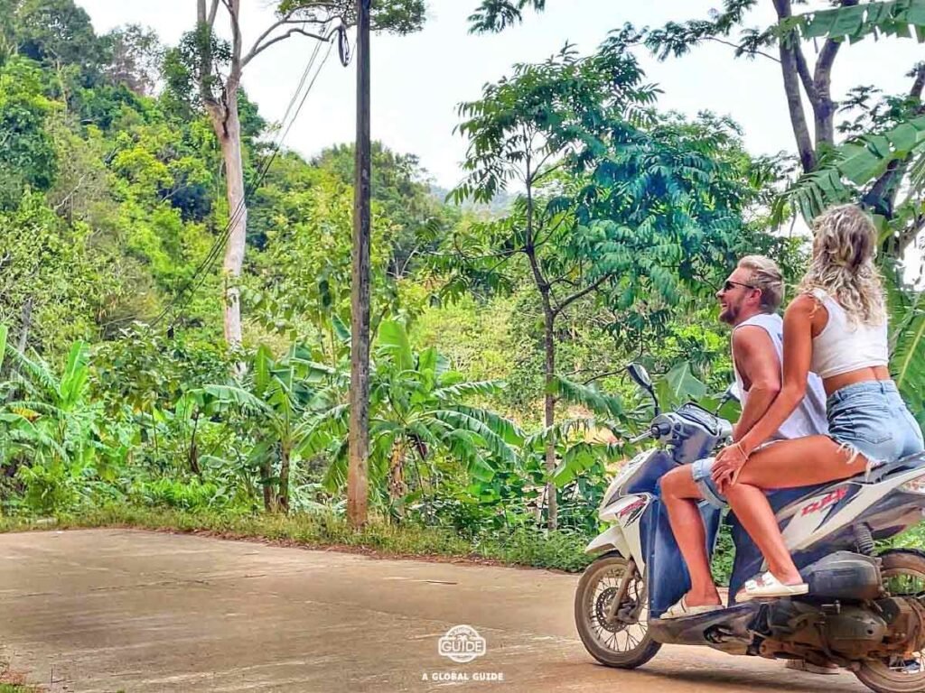 Couple sitting on a moterbike in the jungle. 