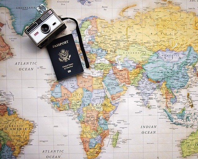 Passport and camera laying on a world map.