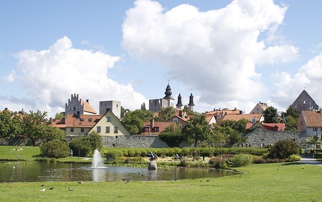 Churches and houses in the background of a fountain and a pond.